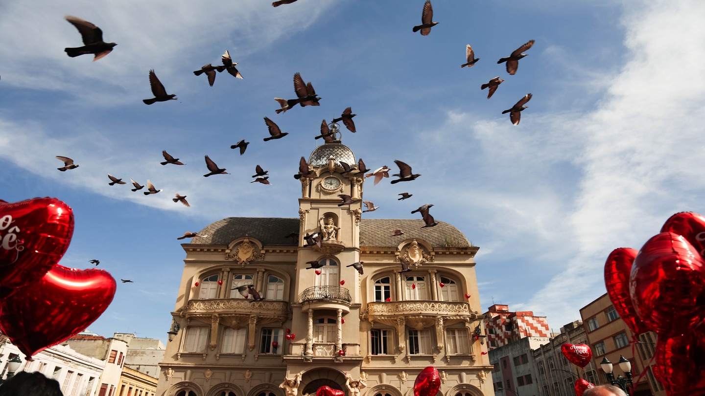 red balloons and birds flying in front of a classical building