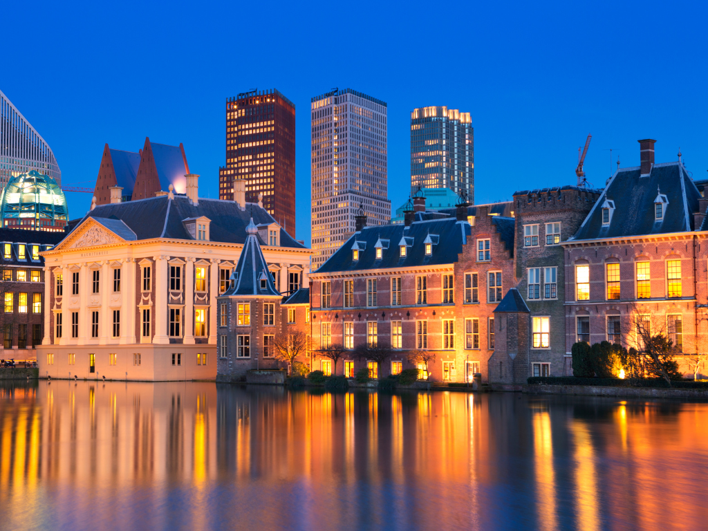 Cardiff's riverfront at night. The lights of the Victorian-era buildings reflect on the glassy river below.