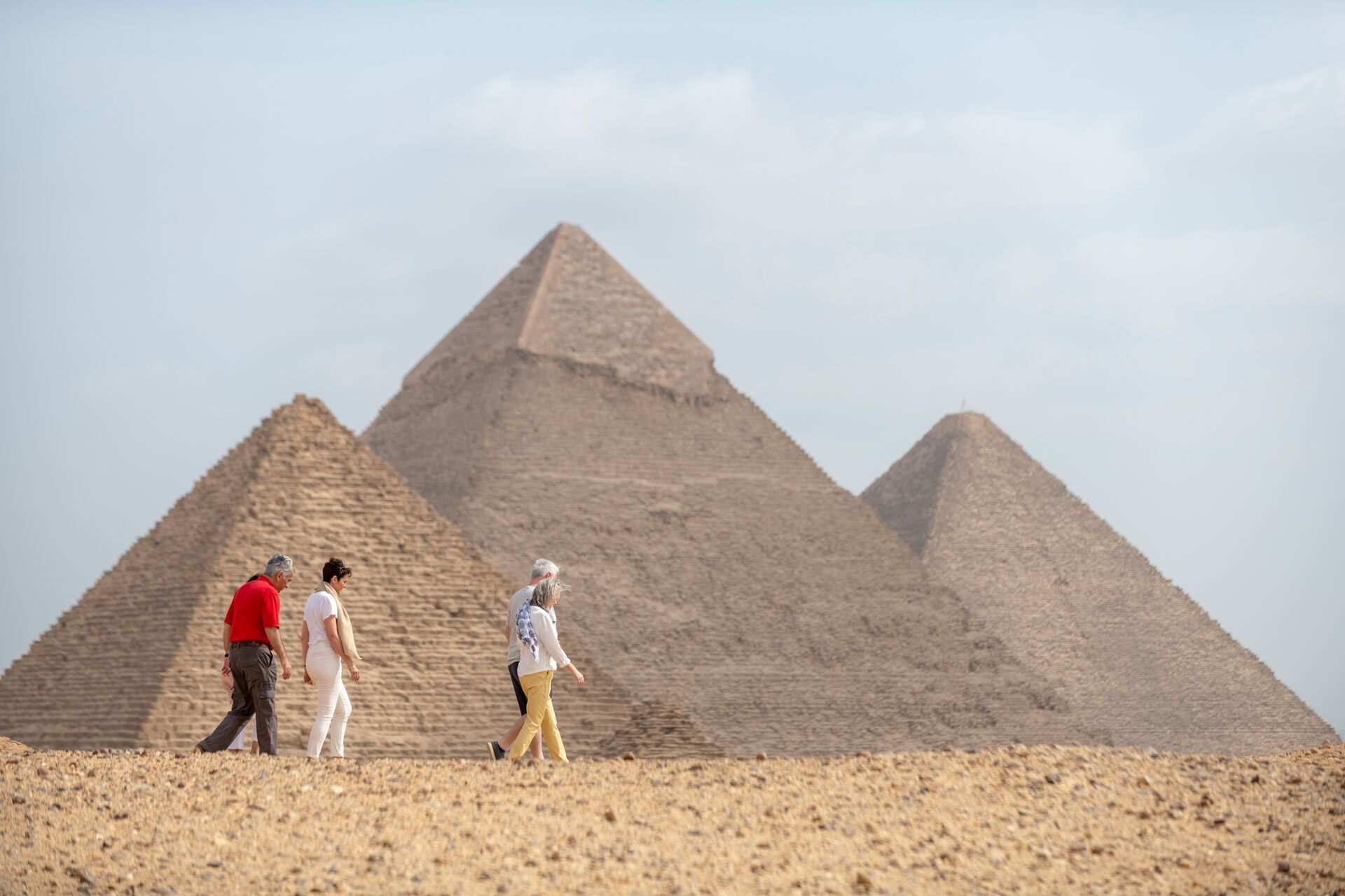 Insight Vacations guests walking inn the sand in Egypt with the three great pyramids in the background