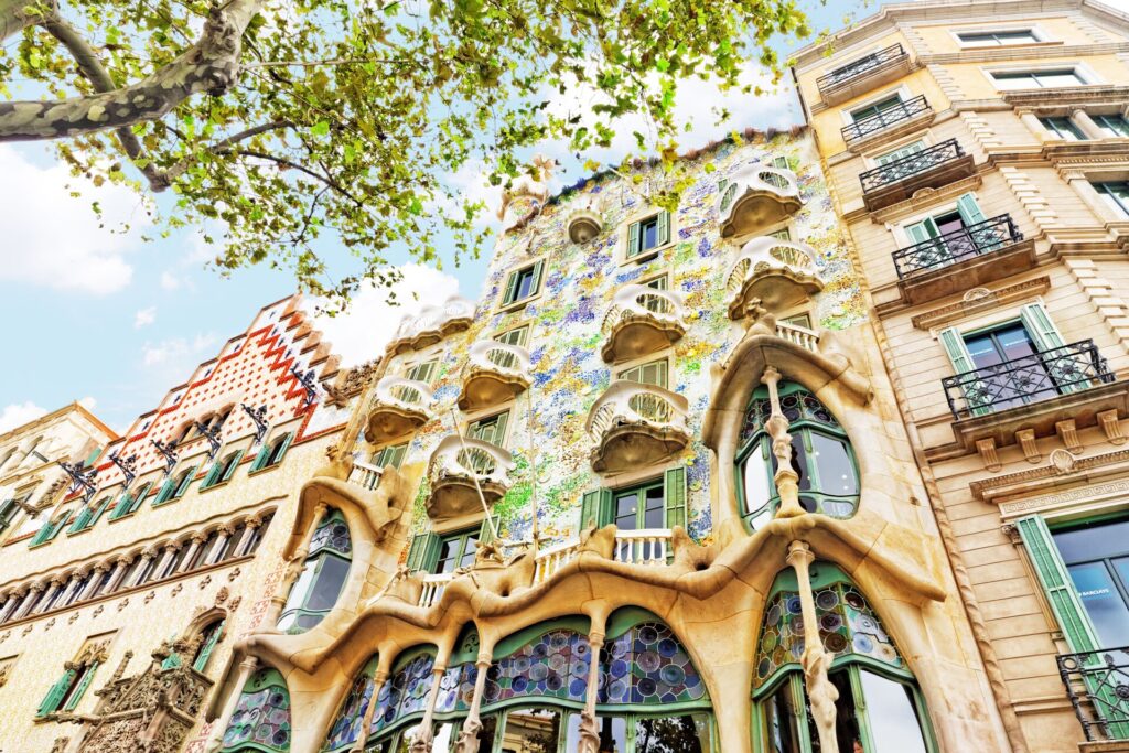 Blue and green ceramic tiles adorn the facade of a tall light brown building in the sunshine