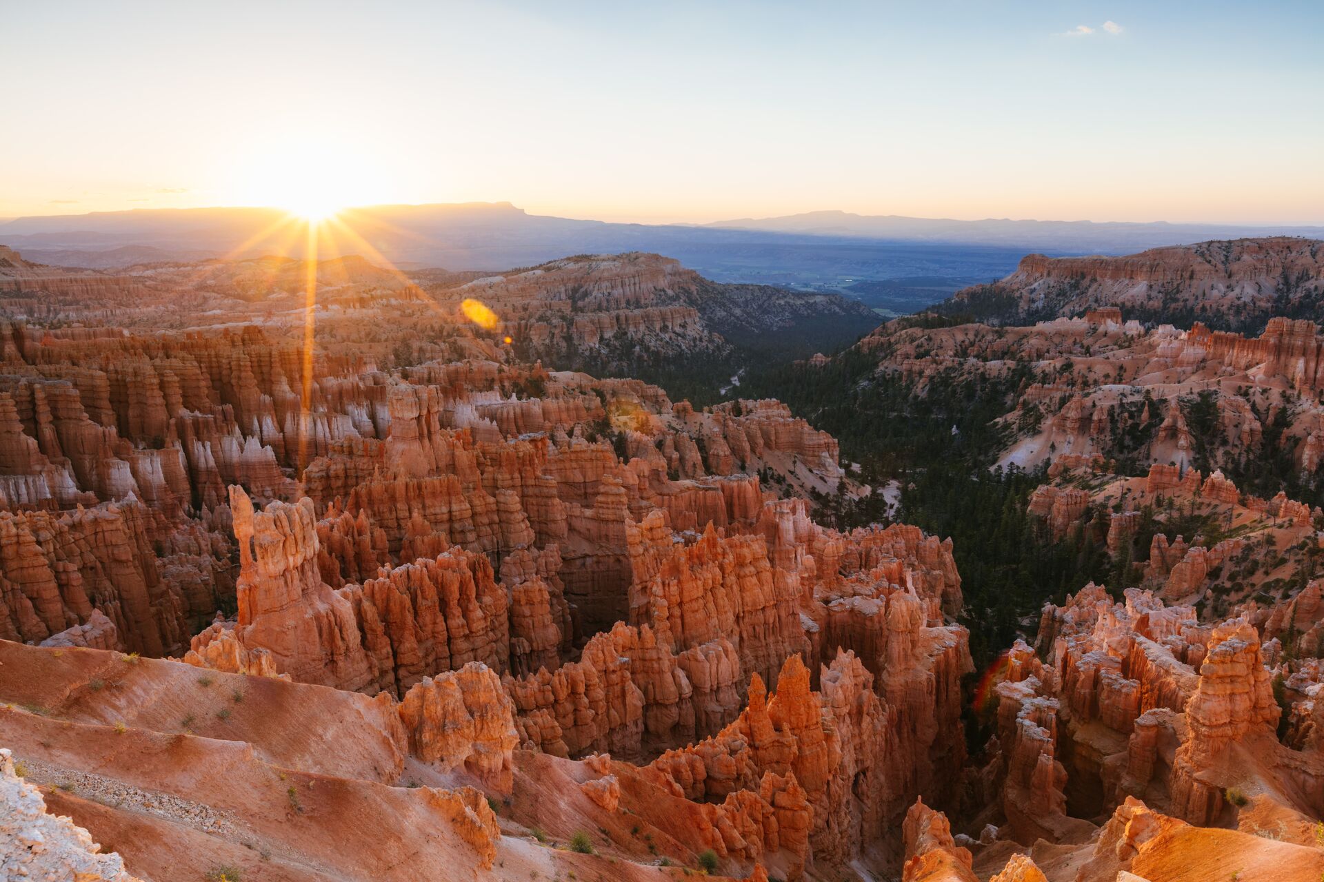 Image fo the sun rise over the Bryce Canyon National Park, over the Hoodoo rock formations glowing warm red