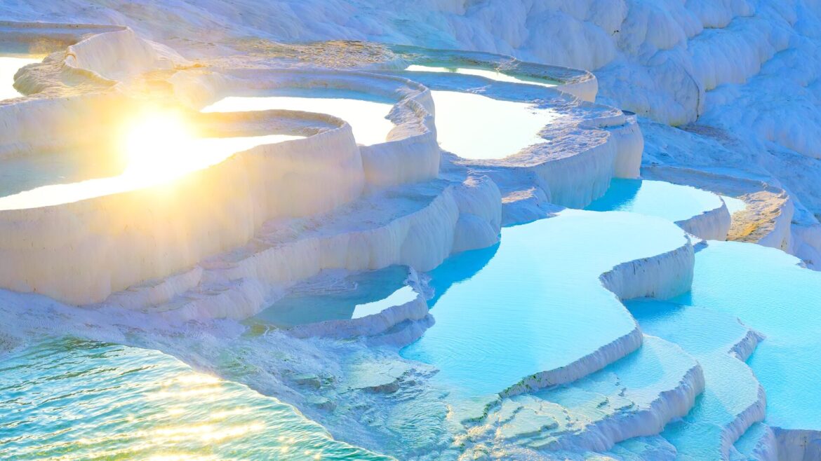 Sun glinting over the bright blue waters of thermal springs located on white limestone terraces, Pamukkale, Turkey