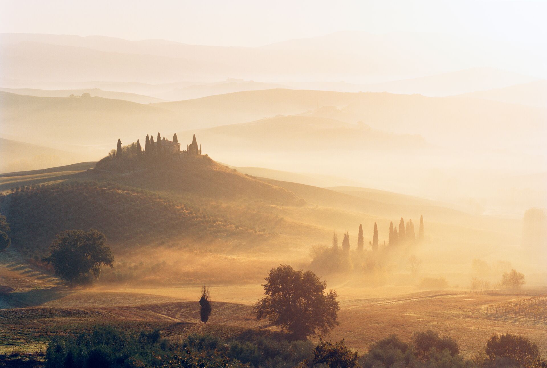Image of Tuscan house on hilltop in the morning sunrise and mist, with a warm orange gloww