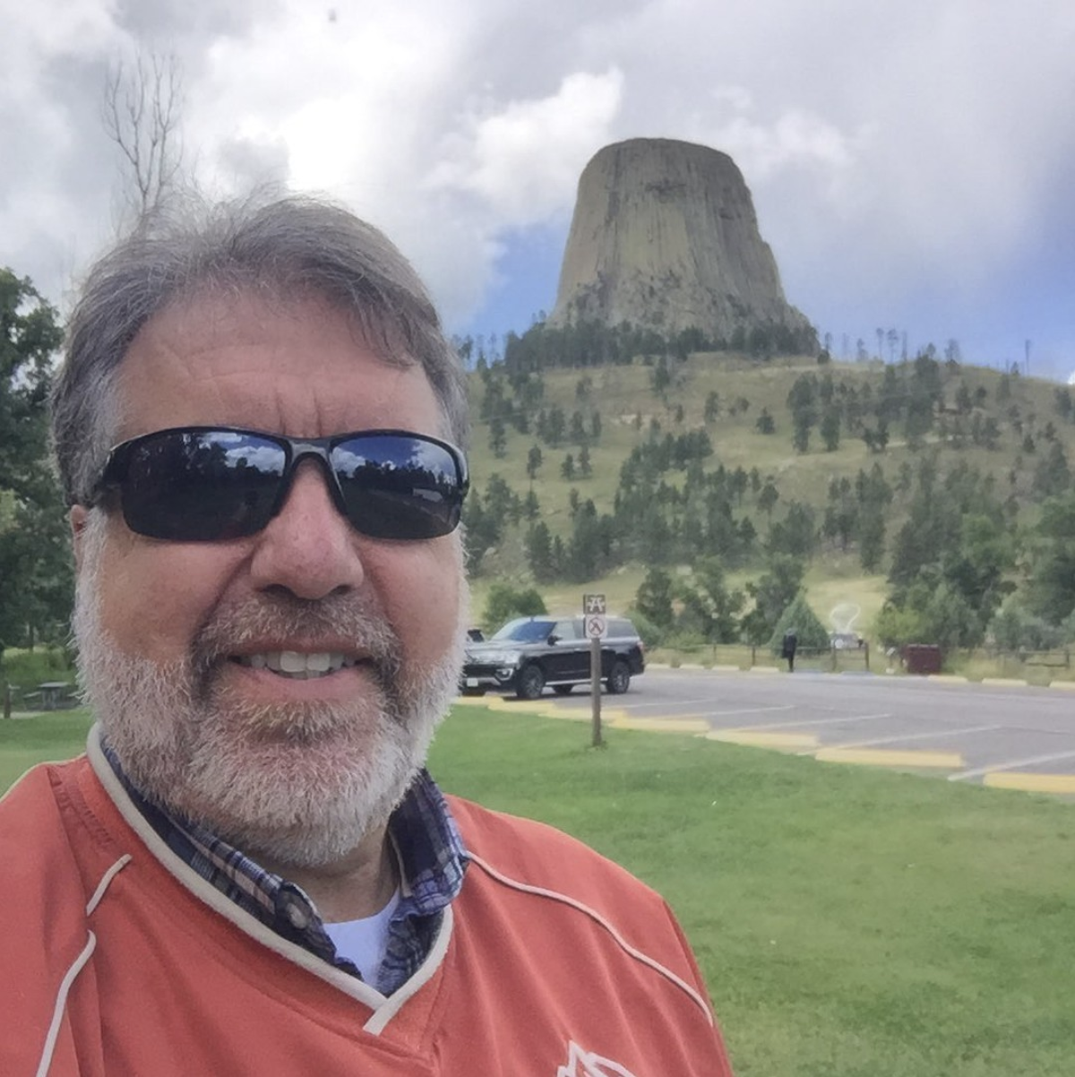 Image of South Dakotas travel expert Randy wearing a red T Shirt and sunglasses with the Crazy Horse Memorial in the background.