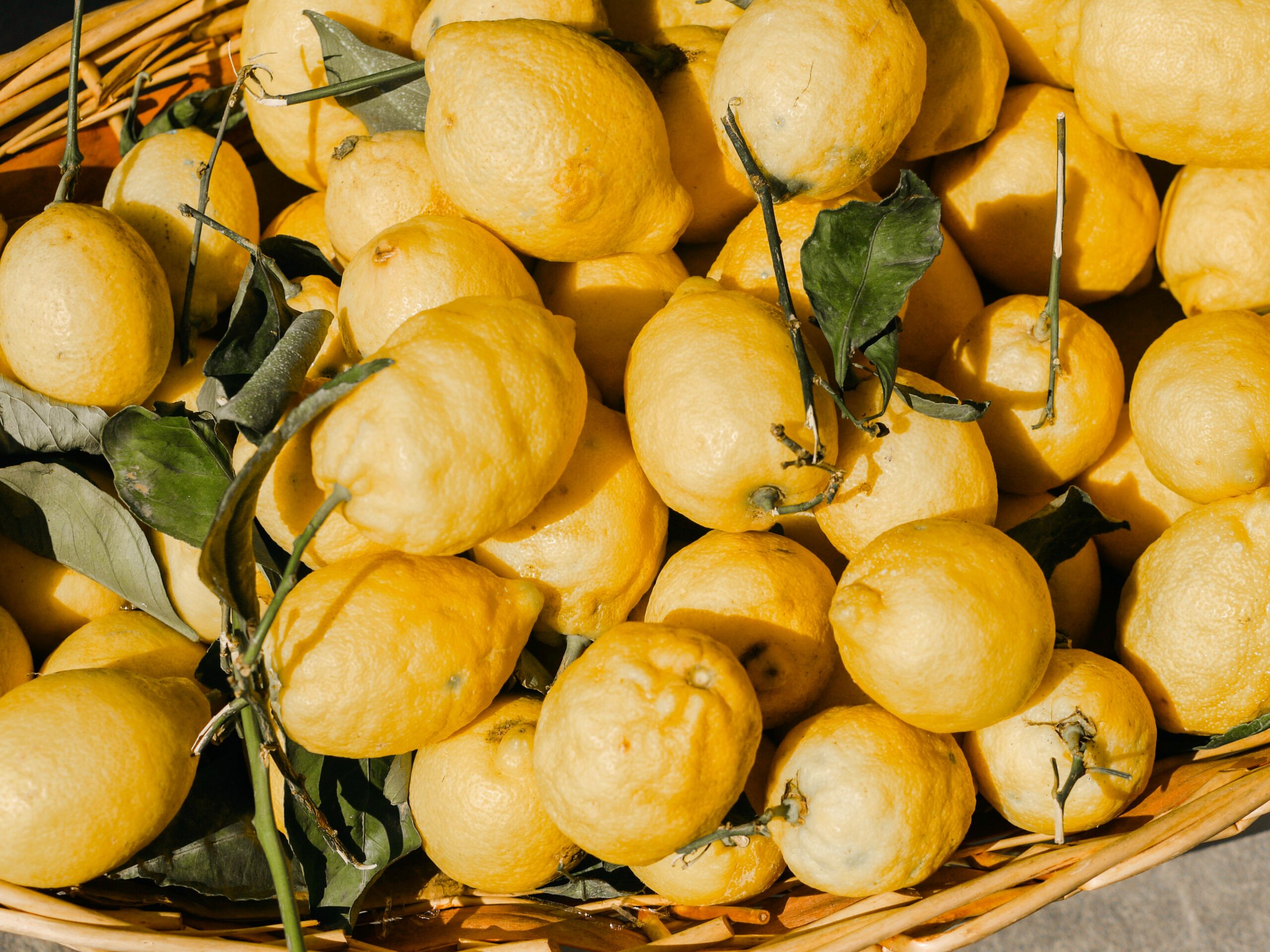 Close up image of a box full of bright yellow lemons,