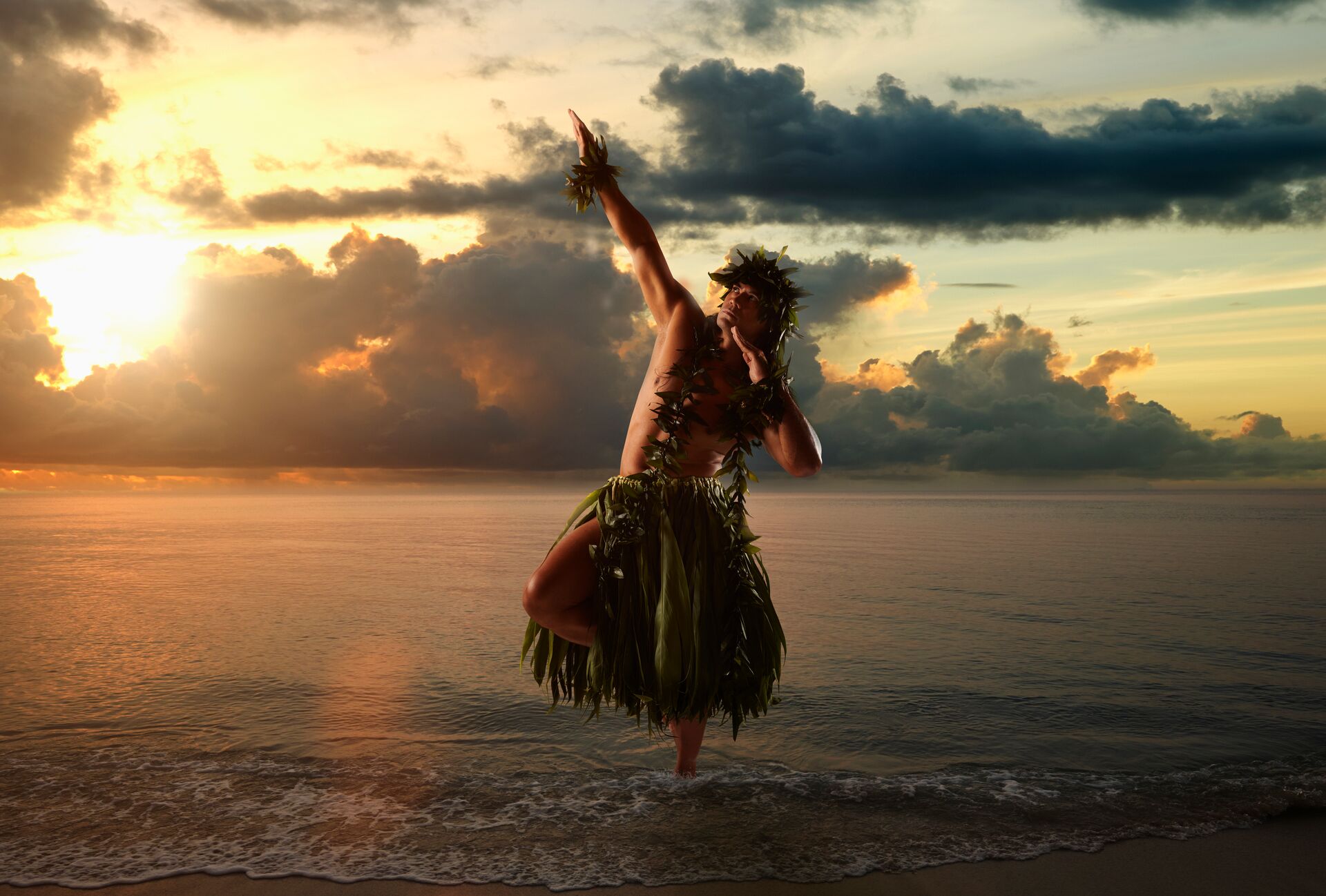 A Hawaiian man dance hula on a beach at sunset wearing traditional grass skirt