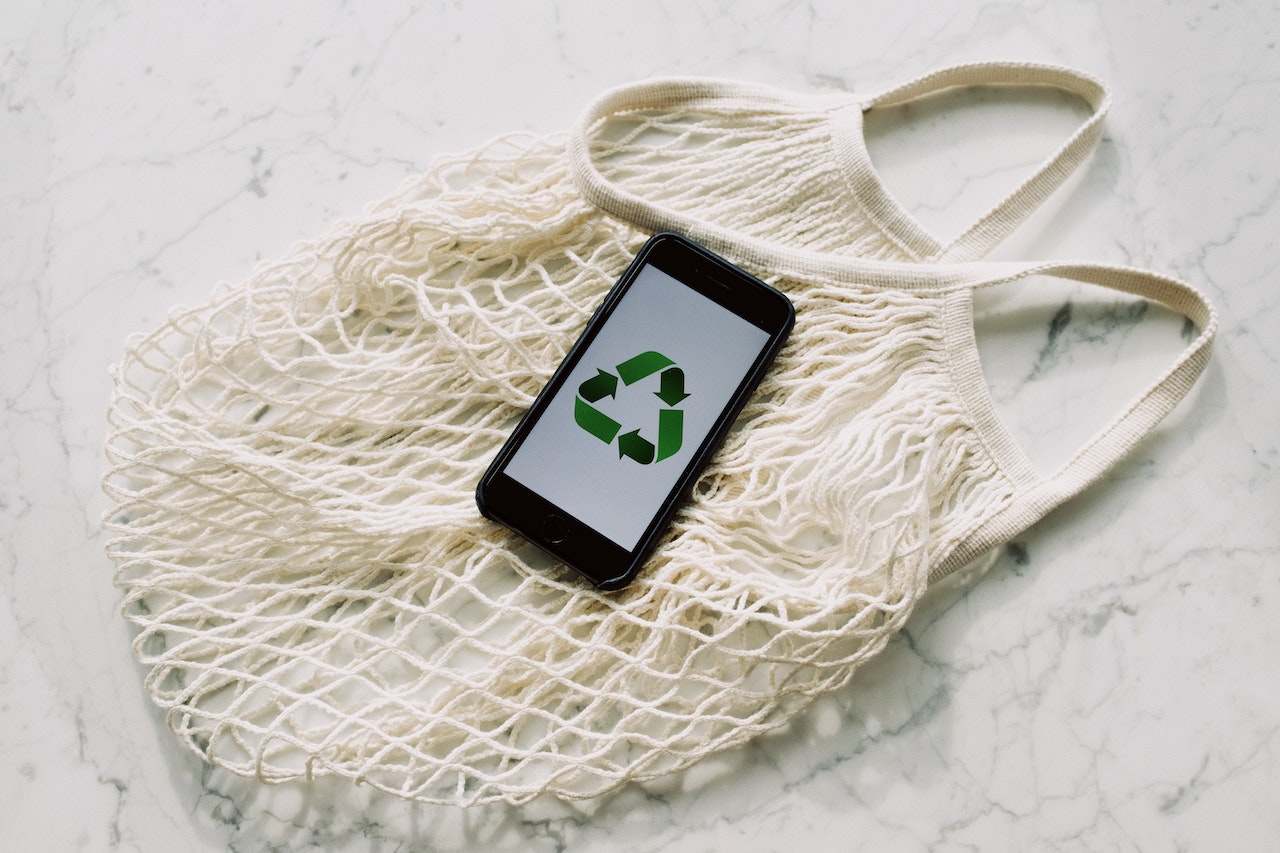 Recycling symbol on phone on rope bag