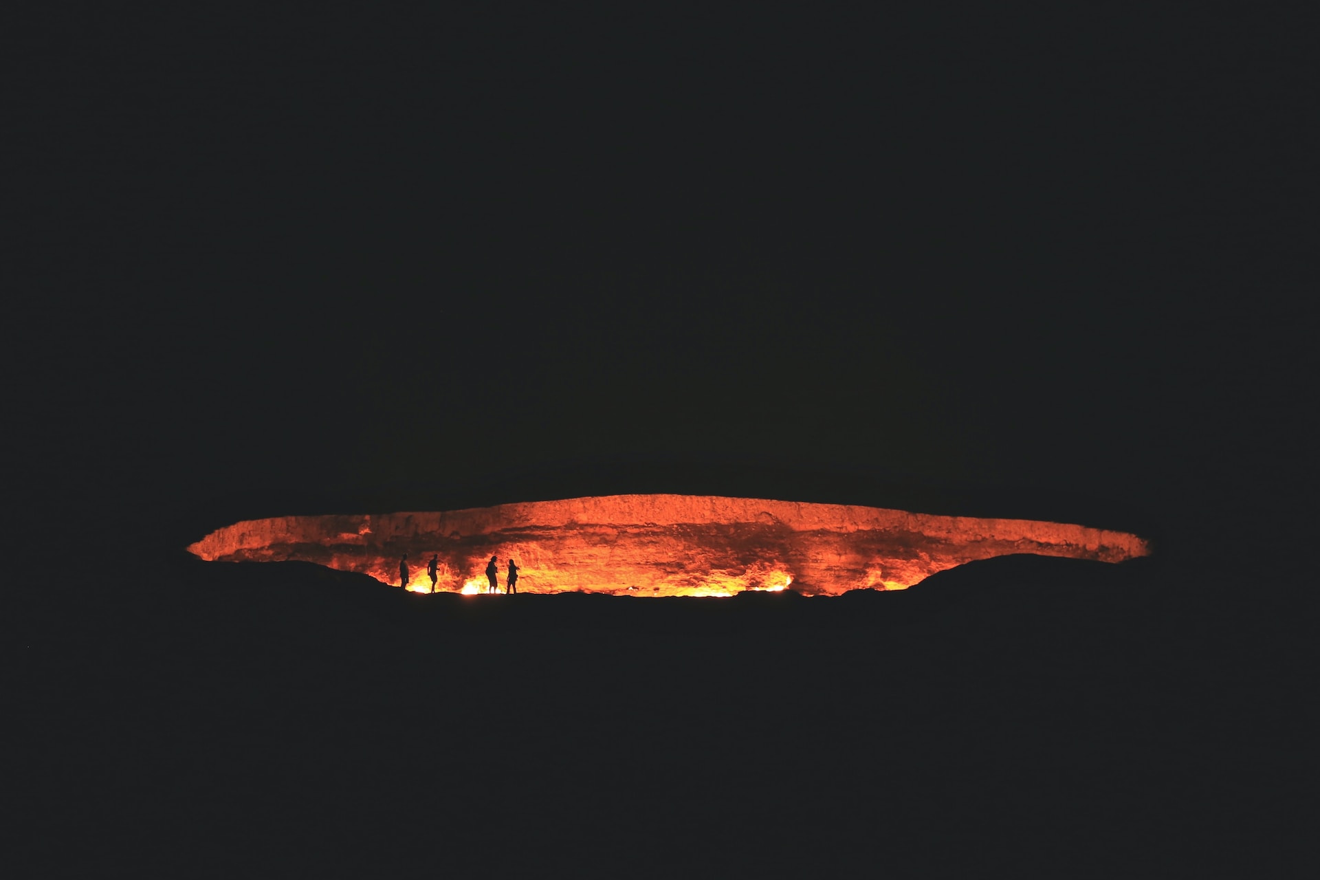 The depression 'Gates of Hell' glowing red as it burns through the night. The rest of the scene is dark.