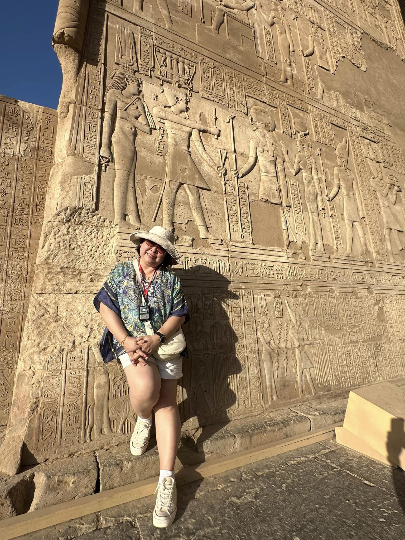 Mae is pictured smiling in from to an Egyptian monument
