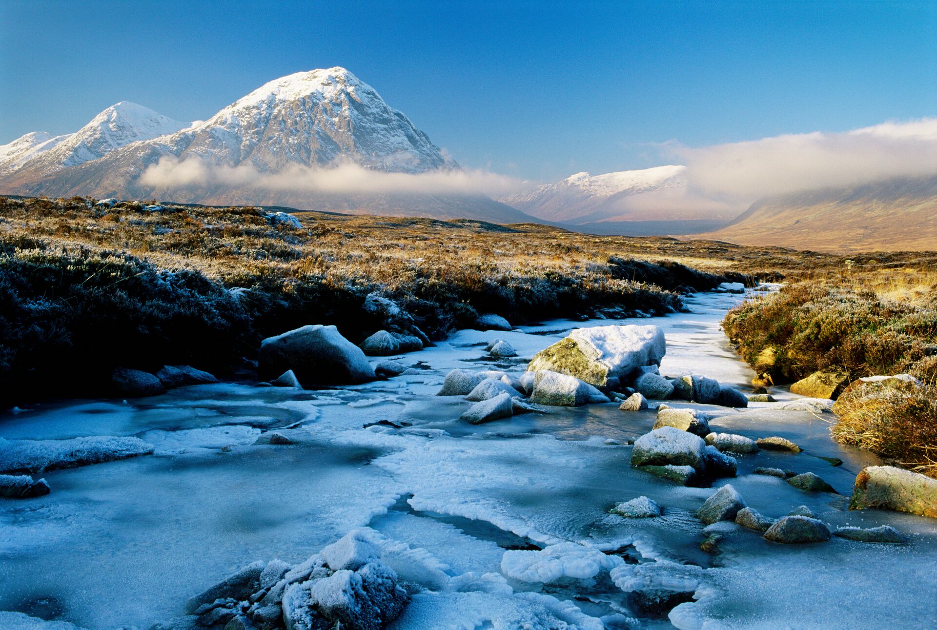 A snow capped mountain stands in the background, with an icy river flowing in the front