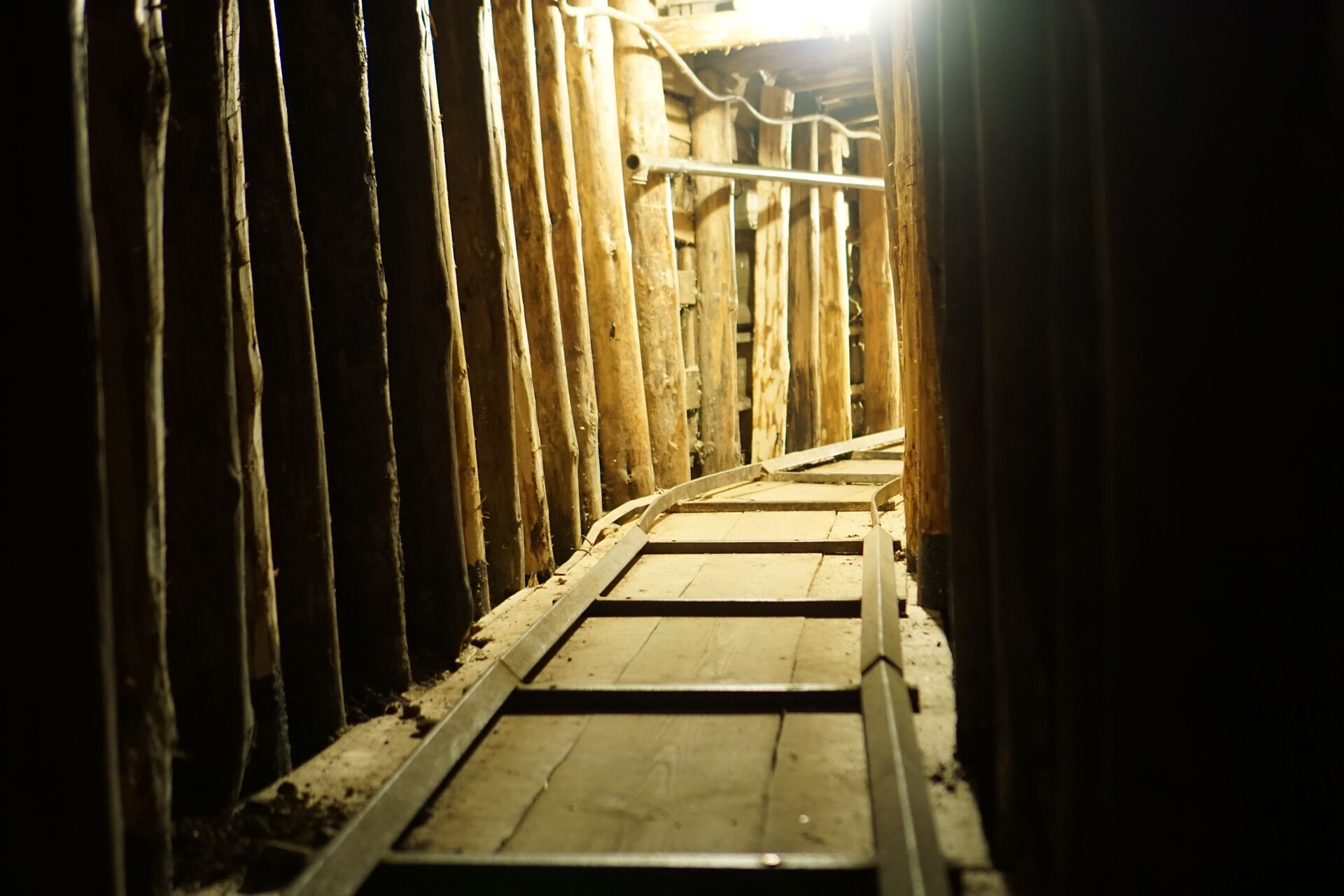 The thin wooden tracks walls of the Tunnel of Hope are shown, with low yellow lighting