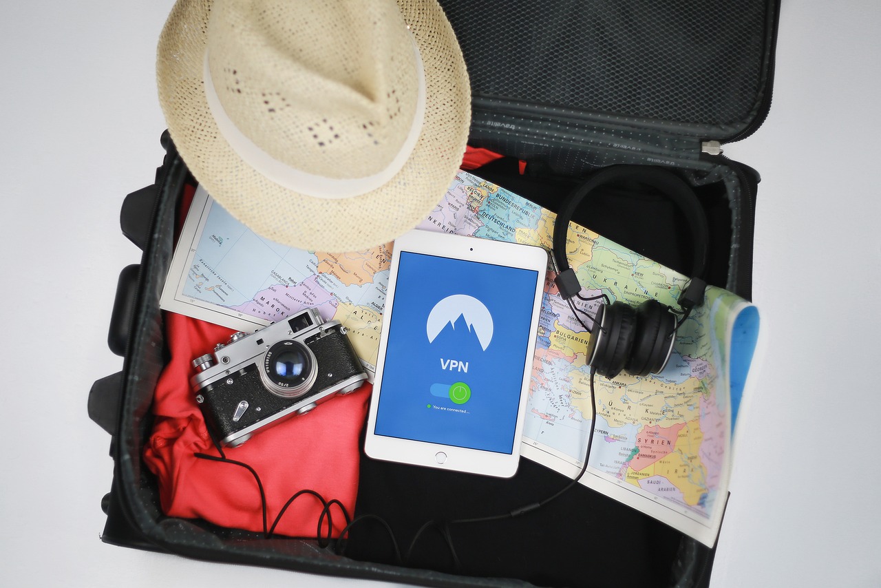 Image of an open suitcase containing a hat, a pair of headphones, a camera and clothes