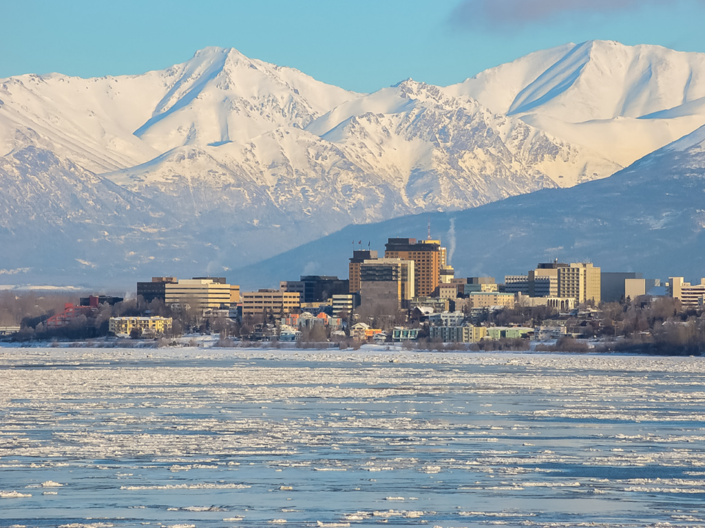 Anchorage, Alaska, by a frozen lake and backdropped by snow-capped mountains
