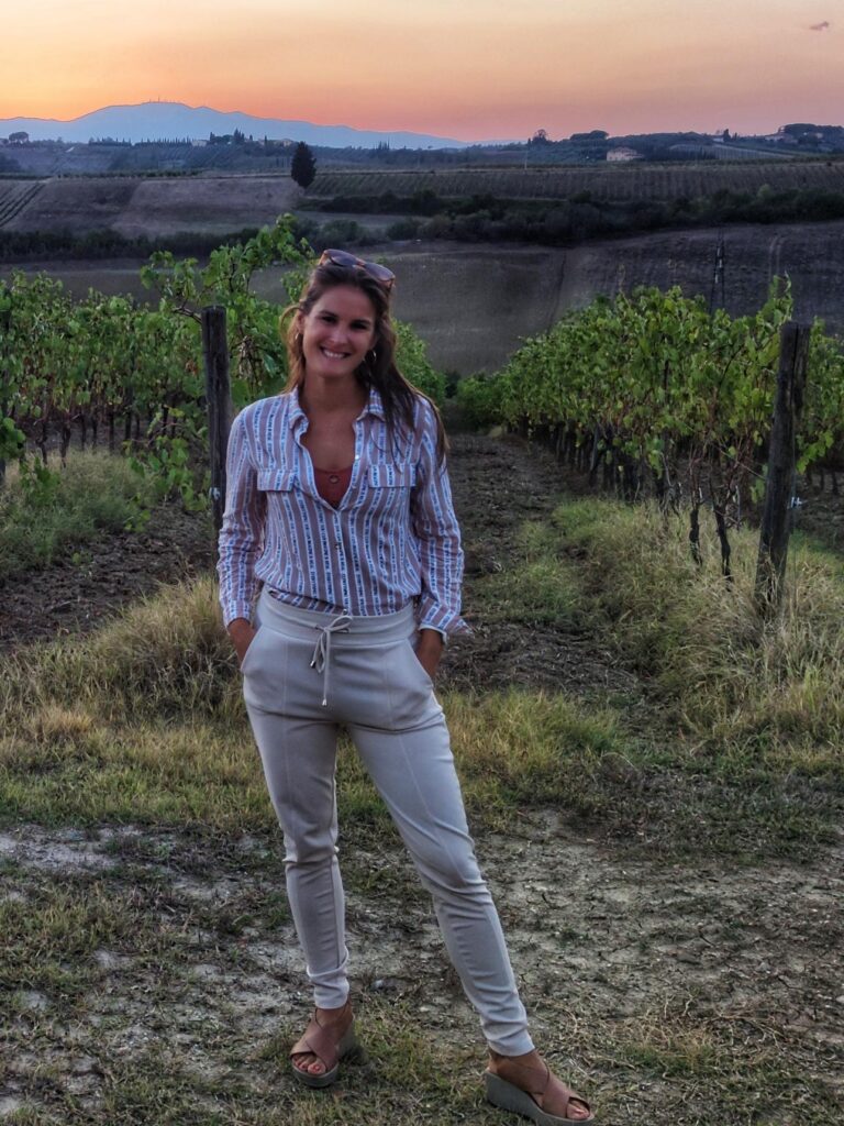 A picture of Vivien, one of our global travel experts, in summery attire standing in front of a background of gorgeous vineyards