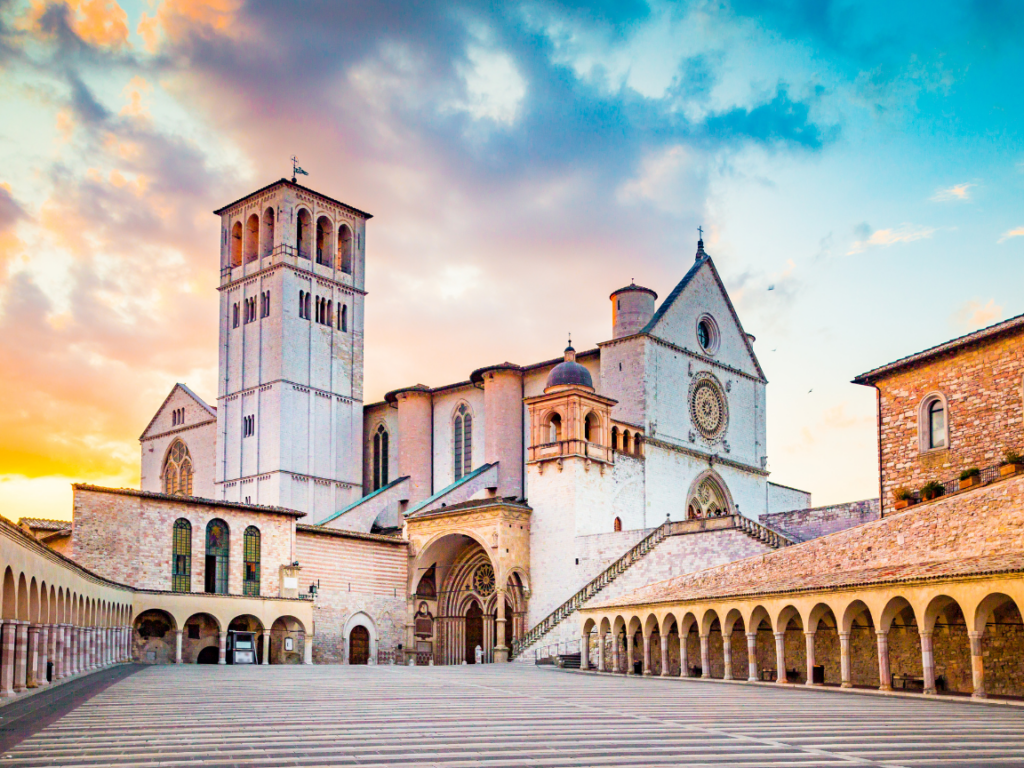 An Assisi church with a clock tower in front of it.