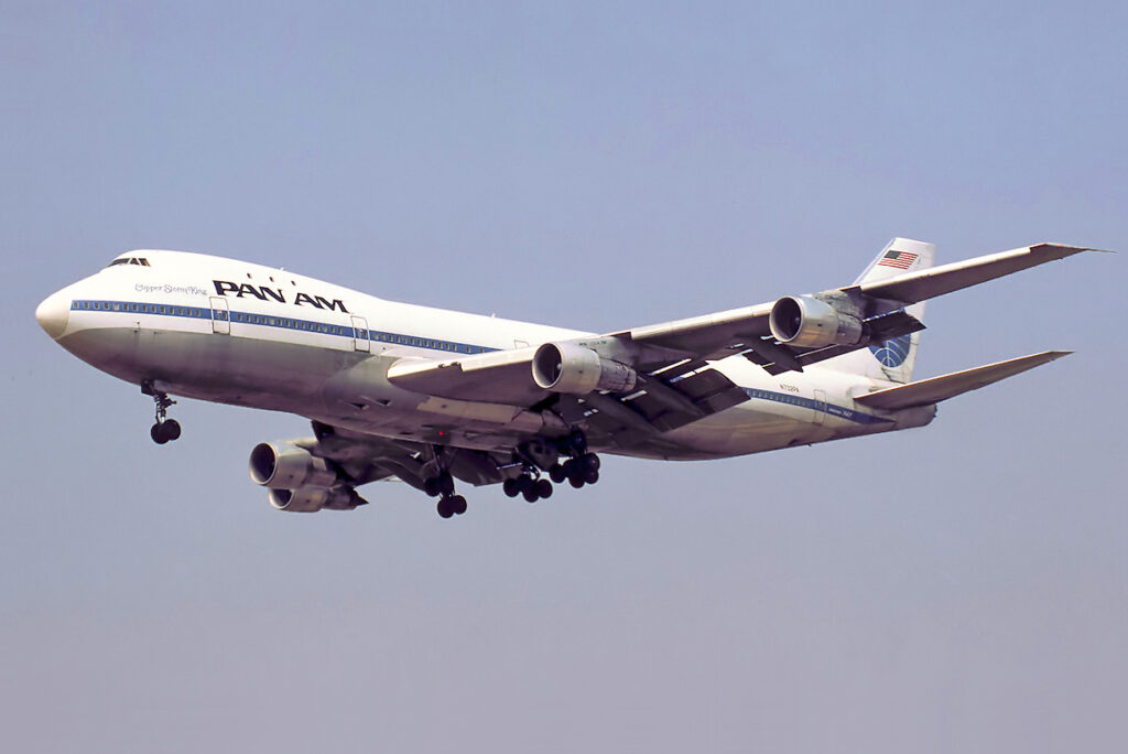 A Pan Am Boeing 747 flies against a blue sky