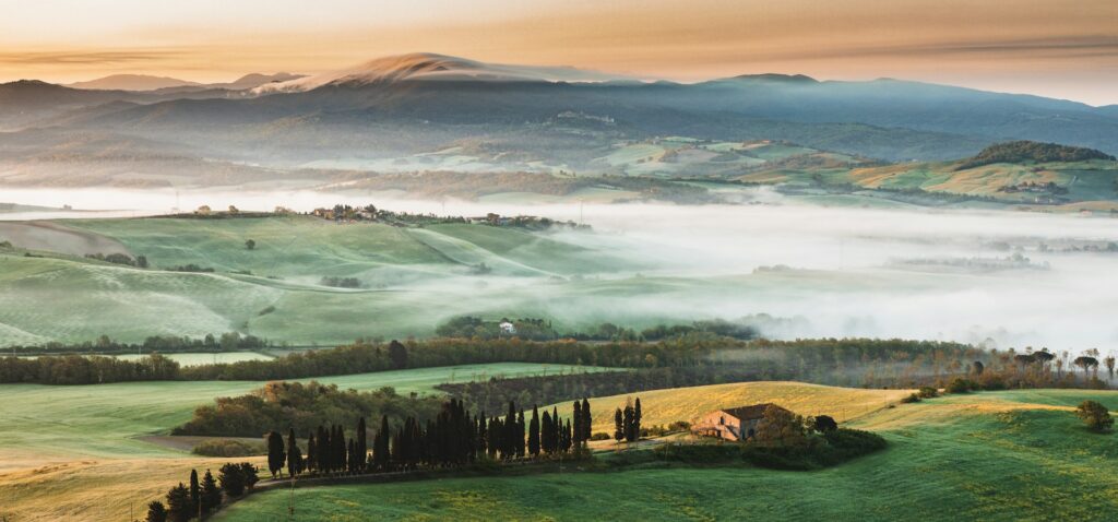 Aerial view of Italian landscape in the spring, with mist-shrouded hillsides, sky is orange at sunrise