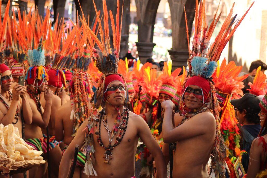 Locals dressed up in traditional garb at the Inti Raymi festival in Cusco. They all adorn orange feather headresses and intricate necklaces.