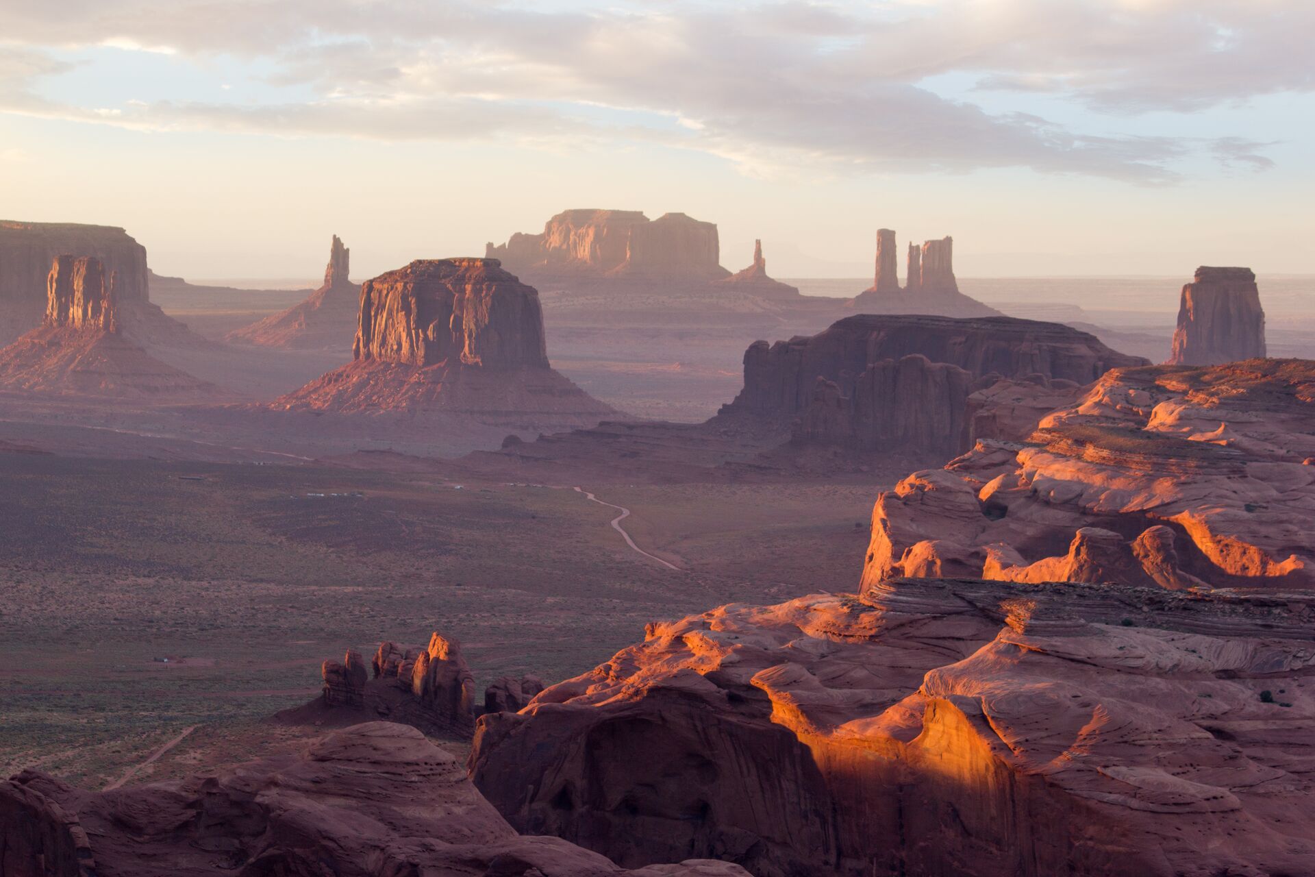 Photograph of Monument Valley, shot from a distance, with sunlight illuminating the buttes and mesas
