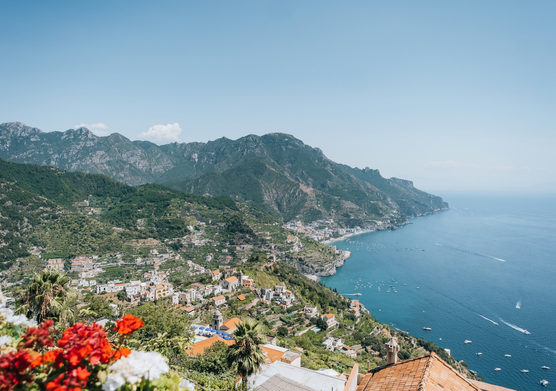 Photograph looking down on the town of Ravello and the Amalfi Coastline, dotted with boats