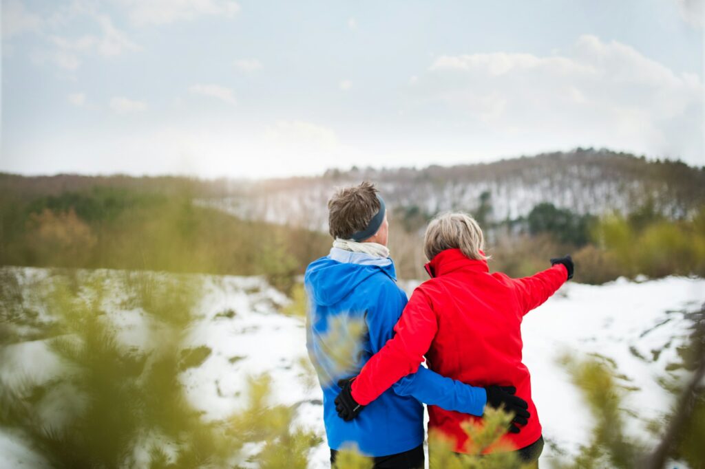 A mature couple, photographed from behind, looking out over a snowy landscape