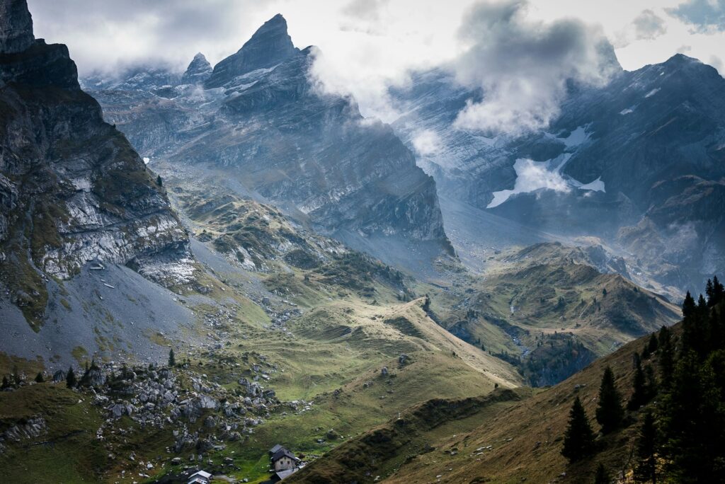 Clouds swirling around a jagged mountain ridge in the Alps