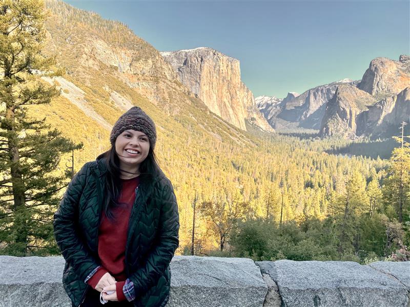 Photo of Maritza sitting on a low wall overlooking Yosemite Valley atYosemite National Park