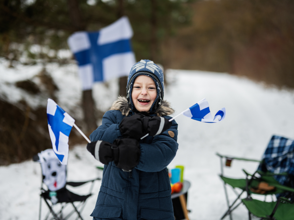 Girl smiling and waving Finland flags