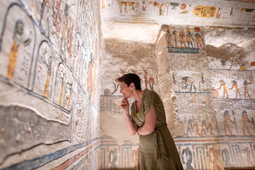 Female Insight guest looking closely at hieroglyphics in a tomb in Egypt
