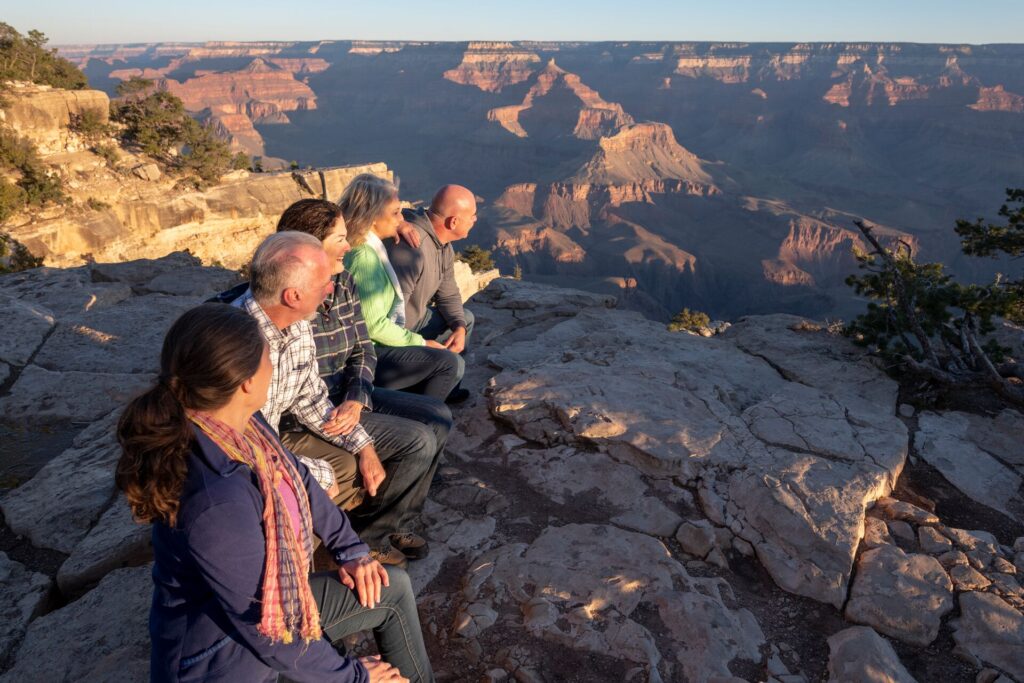 Group of mature travelers looking over Grand Canyon at sunrise 