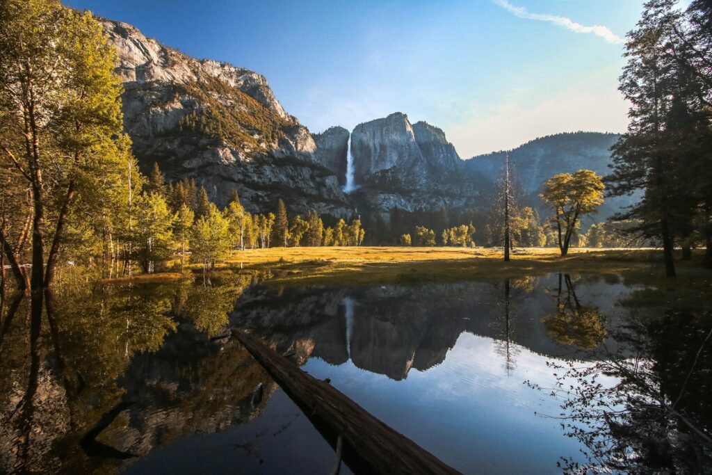 Photo taken off a Bridal Veil Falls in Yosemite National Park, looking across a calm lake, with the park's peaks reflected in the water
