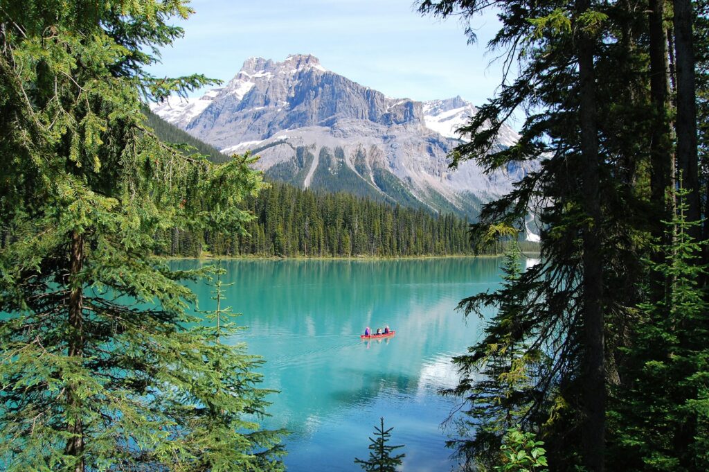 Canoe seen through trees on a blue glacial lake