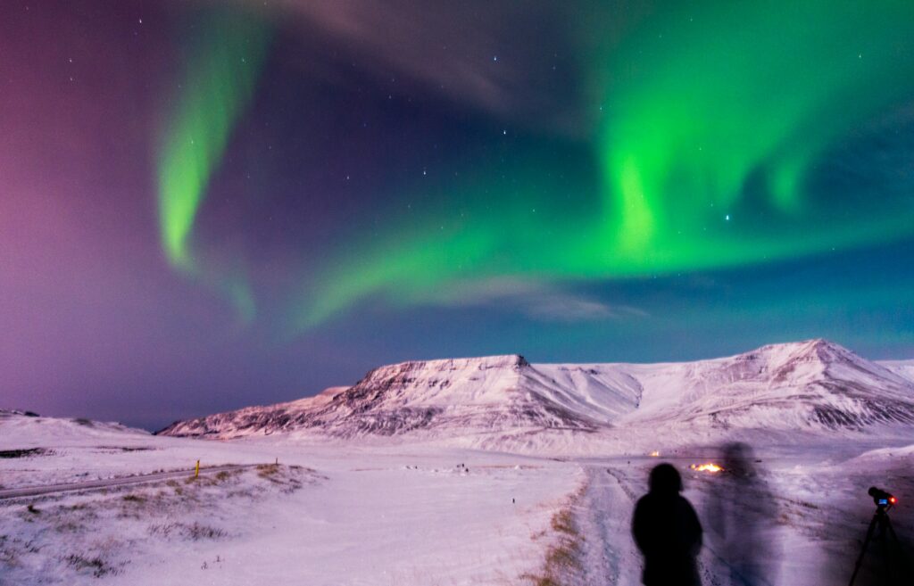 Photographers looking up at the northern lights with their camera on a tripod