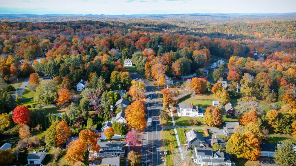 Aerial view of New England town in the fall, surrounded by woodland